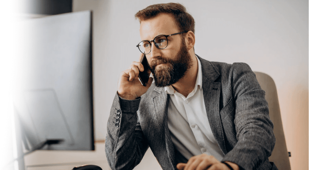 A man sitting at his desk on a Vox VoIP call with a client