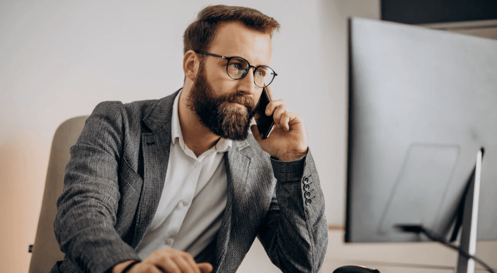 A man sitting at his desk on a Vox VoIP call with a client