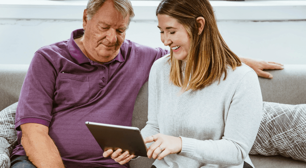 A young girl showing her father how to use social media with their Vox Frogfoot Fibre internet connection