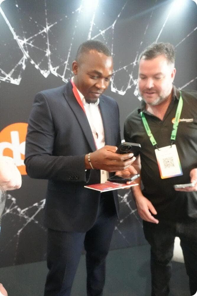 A Zoho team member viewing the Break the Glass app on his phone with DSL Telecom's MD, Dean Schreuder at Zoholics 2026