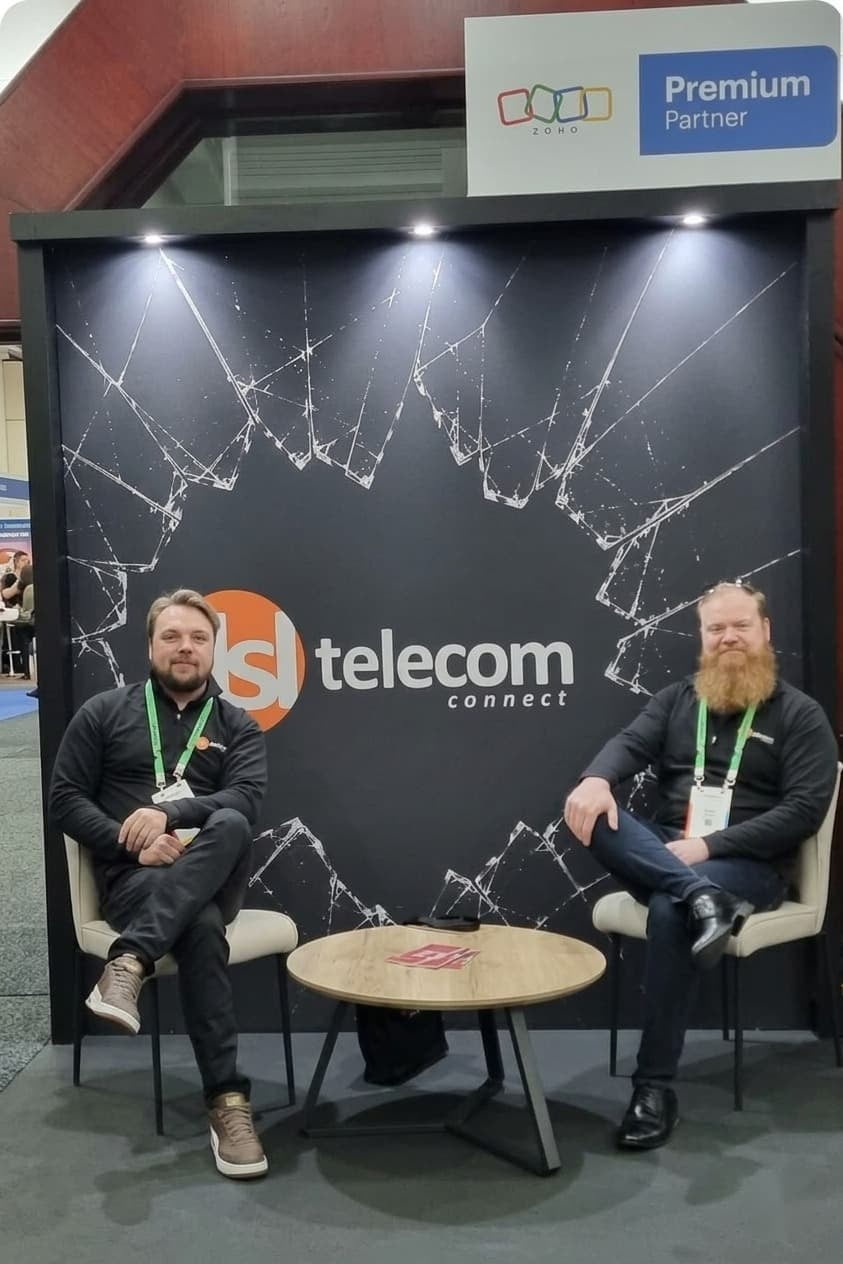 DSL Telecom team members, Hansie and Gerhard, seated either side of the DSL Telecom logo at their Zoholics Johannesburg 2026 stand